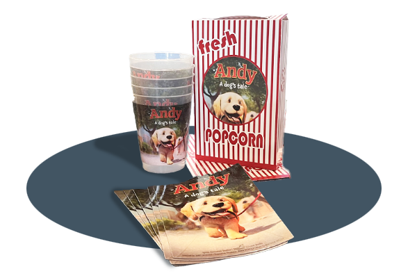 Merchandise set featuring items with "Andy: A Dog's Tale" branding, including plastic cups, a red-and-white striped popcorn bag, and promotional flyers with an image of a smiling dog.